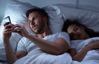 Coppia a letto con smartphone.