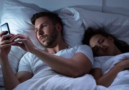Coppia a letto con smartphone.